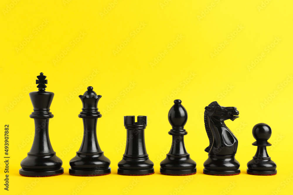 Black chess pieces on yellow background. Space for text