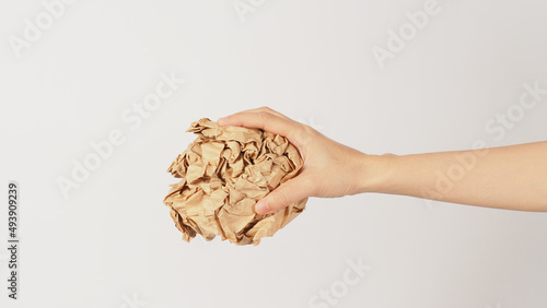 The woman s hand is holding crumpled brown paper on white background.