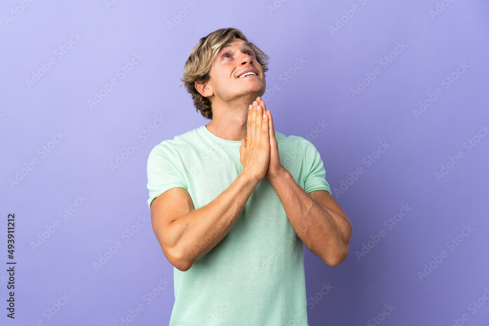 English man over isolated purple background keeps palm together. Person asks for something English man over isolated purple background keeps palm together. Person asks for something