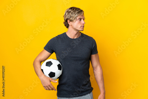 English man over isolated yellow background with soccer ball photo