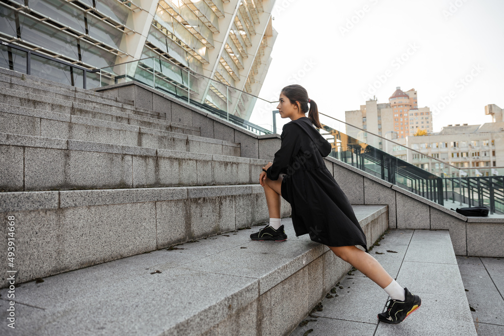Teenage girl doing sports and stretching exercises outdoor of the city background Teenage girl doing sports and stretching exercises outdoor of the city background