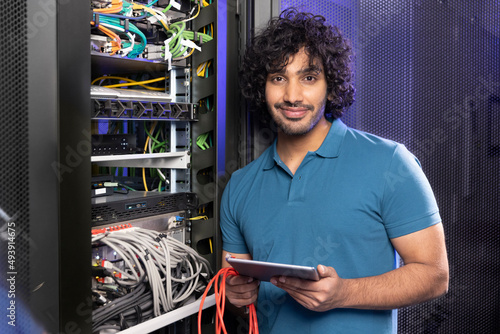 Smiling IT support holding tablet PC standing in server room photo