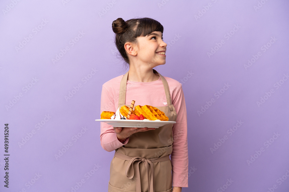 Little caucasian girl holding waffles isolated on purple background thinking an idea while looking up Little caucasian girl holding waffles isolated on purple background thinking an idea while looking up