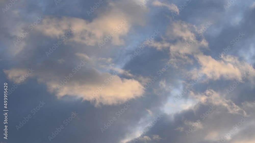 Small puffy cumulus clouds forming below altocumulus radiatus and passing over sky at sunset evening
