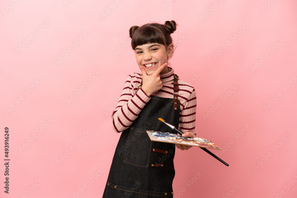 Little artist girl holding a palette isolated on pink background happy and smiling Little artist girl holding a palette isolated on pink background happy and smiling