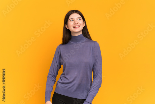 Young Ukrainian girl isolated on yellow background thinking an idea while looking up © luismolinero
