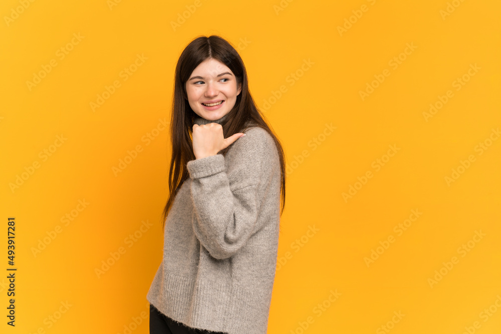 Young Ukrainian girl isolated on yellow background pointing to the side to present a product Young Ukrainian girl isolated on yellow background pointing to the side to present a product