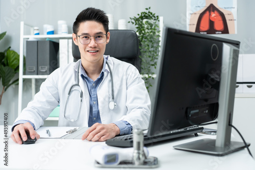 Portrait of handsome physician doctor sit on table in office hospital. 