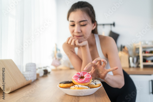 Asian beautiful young girl hungry and want to eat donut in kitchen. 