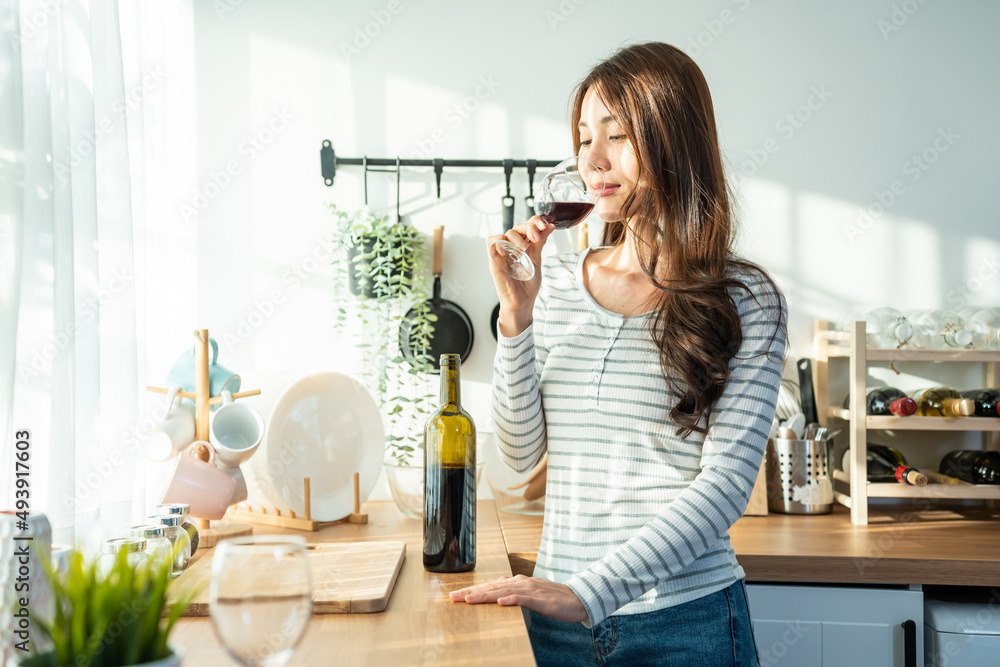 Asian attractive young woman drinking wine in glass in kitchen at home. Asian attractive young woman drinking wine in glass in kitchen at home.