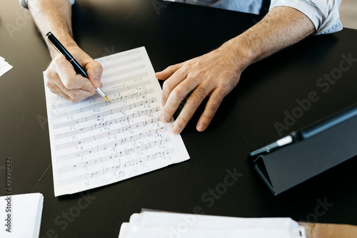 Musician writing musical notes by tablet PC at table