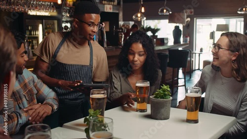 African American waiter taking orders from customers on digital tablet