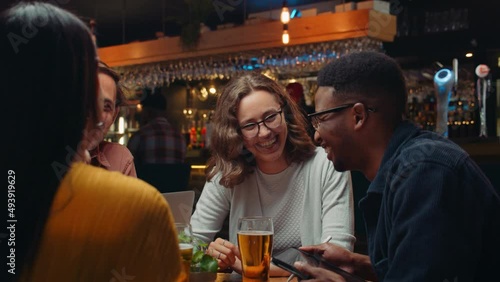 Diverse group of work colleagues out for drinks chatting and laughing