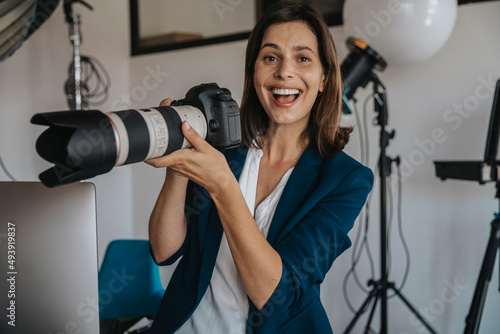 Cheerful photographer holding digital camera in studio photo