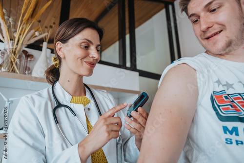 Smiling doctor doing blood glucose test of patient in clinic photo