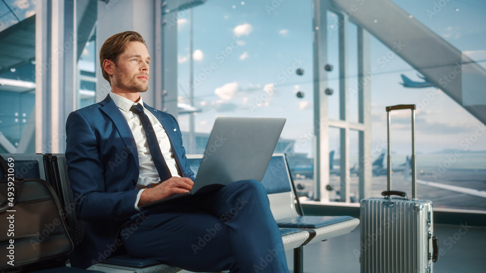 Airport Terminal: Businessman Uses Laptop Computer, Waiting for Flight to International Conference. Traveling Entrepreneur Remote Work Online Sitting in a Boarding Lounge of Airline Hub with Airplanes Airport Terminal: Businessman Uses Laptop Computer, Waiting for Flight to International Conference. Traveling Entrepreneur Remote Work Online Sitting in a Boarding Lounge of Airline Hub with Airplanes