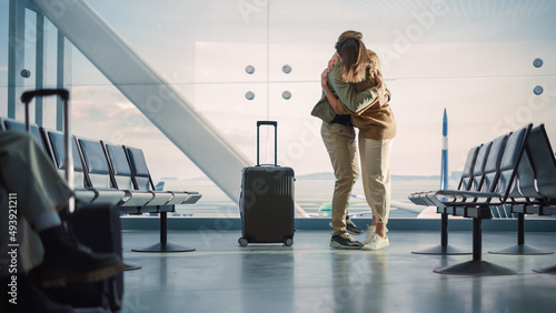 Airport Terminal Family Reunion: Beauitful Couple Meets at the Boarding Lounge. Smiling Girlfiend Meets the Love of Her Life after Long Parting and Hugs and Dances with Her Handsome Partner photo