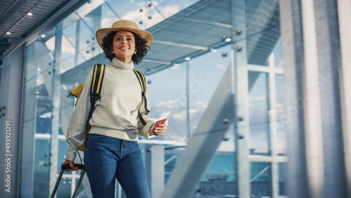 Foto Airport Terminal: Beautiful Smiling Black Woman Holds Ticket, Walks Through in Airline Hub to the Gates Where Airplane Waits