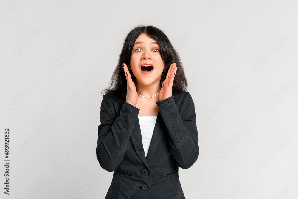 Wow. Young emotional surprised dark-haired girl standing with open mouth and keeping hands on cheeks, smiling and shouting. Good news or joy concept Wow. Young emotional surprised dark-haired girl standing with open mouth and keeping hands on cheeks, smiling and shouting. Good news or joy concept
