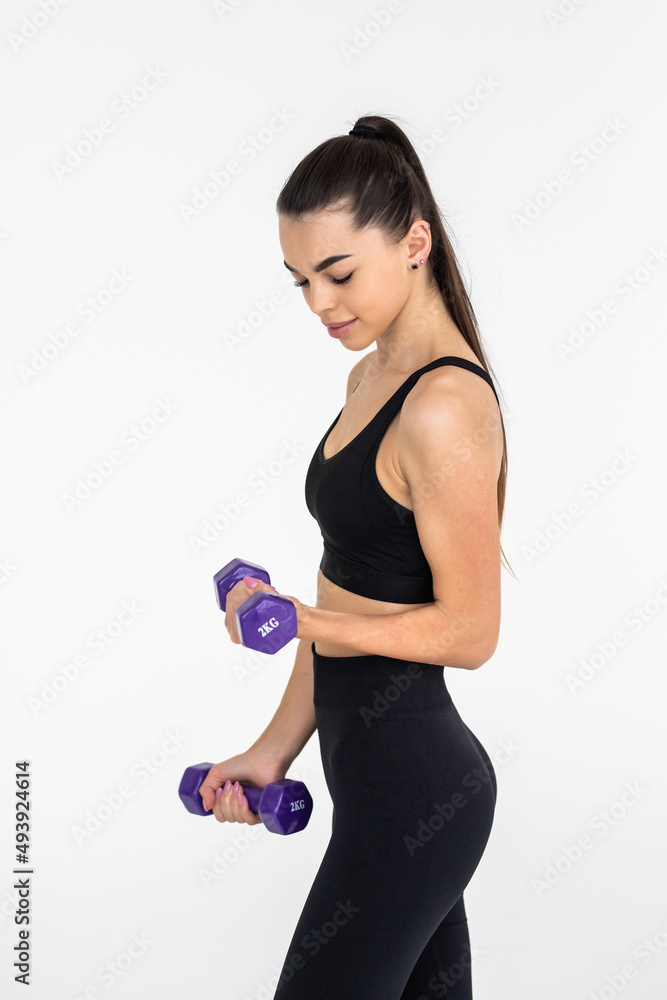 Young beautiful woman doing exercises with dumbbell in gym. Young beautiful woman doing exercises with dumbbell in gym.