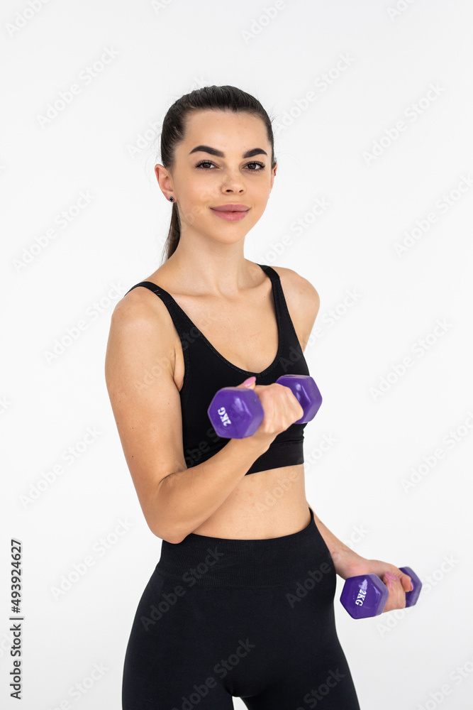 Young beautiful woman doing exercises with dumbbell in gym. Young beautiful woman doing exercises with dumbbell in gym.