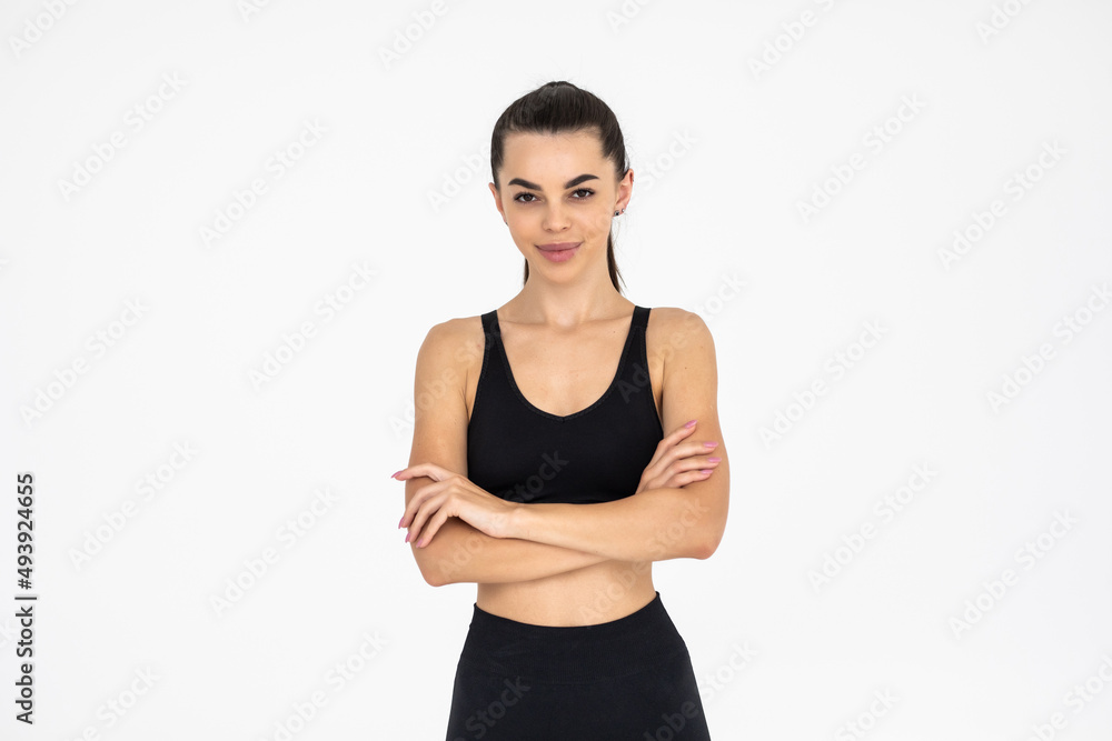 Smiling sports woman standing with arms folded and looking at camera on a white background Smiling sports woman standing with arms folded and looking at camera on a white background