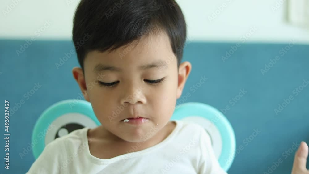 CU Portrait of children boy (3-4) enjoy eating breakfast at the children's dining table at home. CU Portrait of children boy (3-4) enjoy eating breakfast at the children's dining table at home.