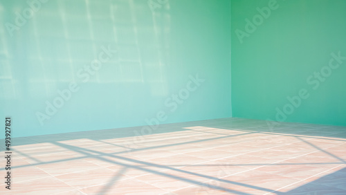 Sunlight and shadow on marble tile floor surface with green cement wall in empty room inside of house construction site, perspective side view