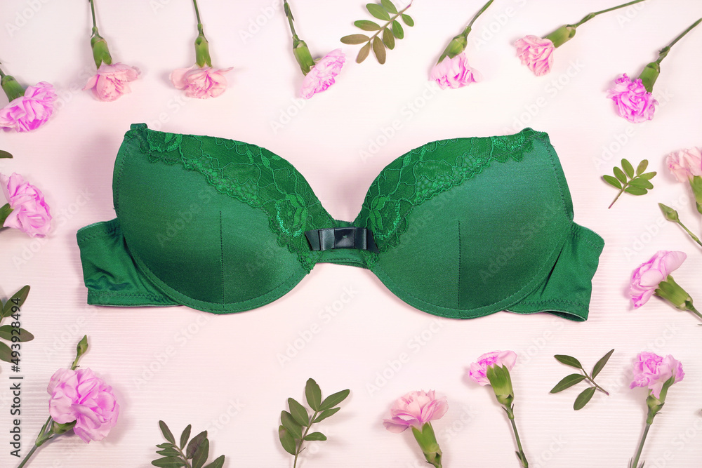 Beautiful green bra surrounded by flowers, white background, top view. Stylish lingerie, underwear. Beautiful green bra surrounded by flowers, white background, top view. Stylish lingerie, underwear.