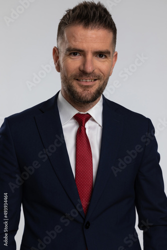 unshaved businessman in suit in his forties smiling and posing