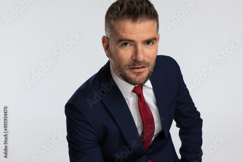sexy bearded man wearing navy blue suit and red tie posing