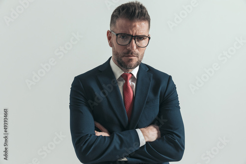 serious businessman with eyeglasses crossing arms and frowning