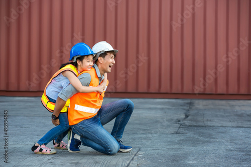 Father and little daughter wearing a safety helmet at Container cargo site. Business heir concept. Happy father and daughter wearing safety helmet work site. Business heir concept. © kanpisut