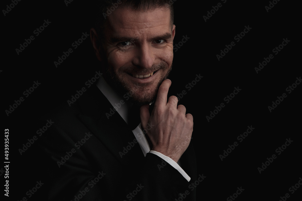 close up of attractive businessman touching beard and smiling