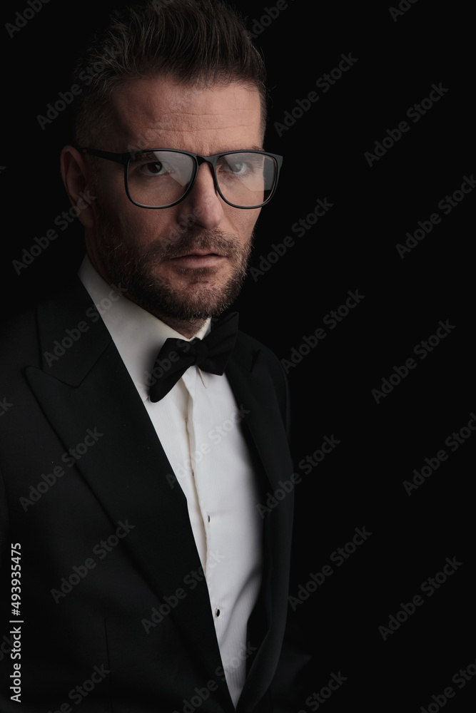 portrait of man in tuxedo with glasses looking away portrait of man in tuxedo with glasses looking away
