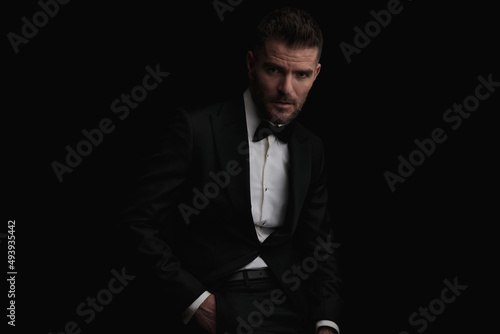 sexy mysterious man in tuxedo holding hand in pocket