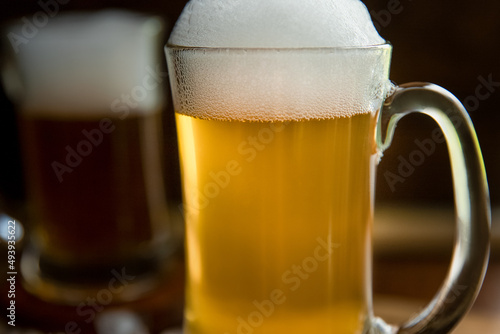 fresh beer with bubbles in a glass mug over dark wooden background in a pub or bar
