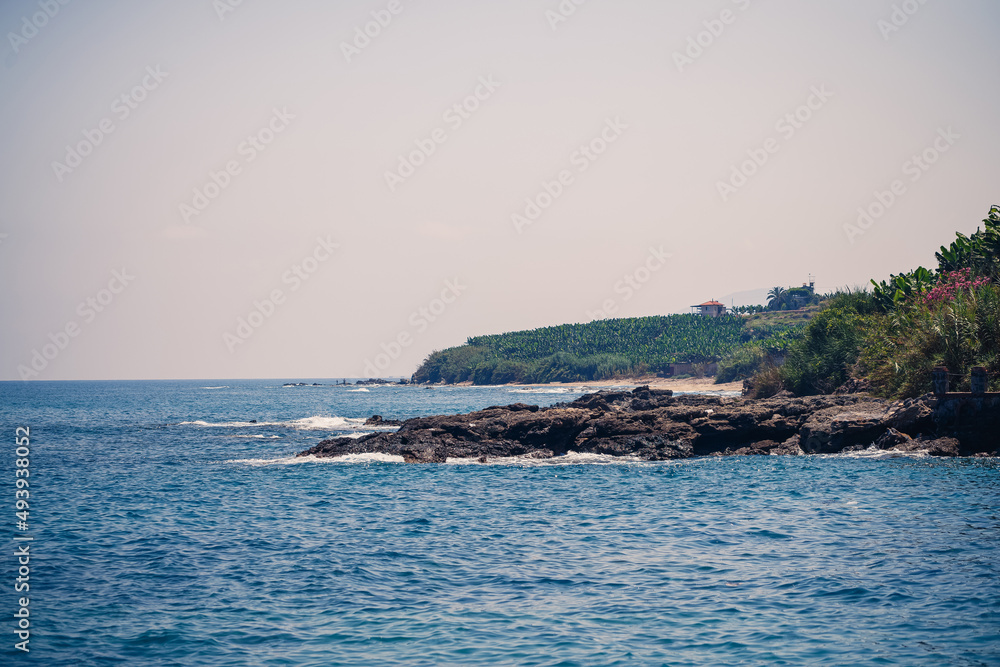 A view of the Mediterranean coast with waves of azure water. Summer seascape. Seaside in sunny weather. Beautiful sea view