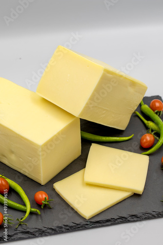 Cheddar cheese or kashkaval cheese on white background. Cheese slices on the serving board photo