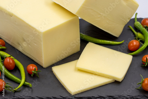 Cheddar cheese or kashkaval cheese on white background. Cheese slices on the serving board photo