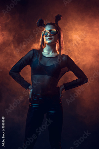 Portrait of beautiful cyber model woman posing wearing led glasses on head with neon light in a virtual tech environment