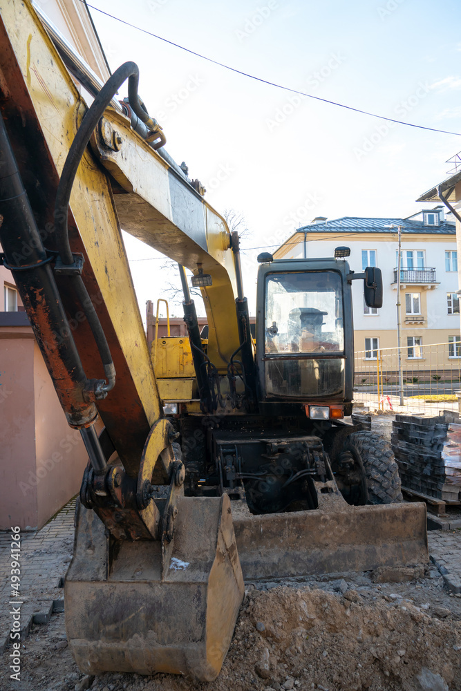 The excavator is working on the construction site to replace the pipeline in winter. Digging holes for laying new pipes for central heating in a residential area. The excavator is working on the construction site to replace the pipeline in winter. Digging holes for laying new pipes for central heating in a residential area.