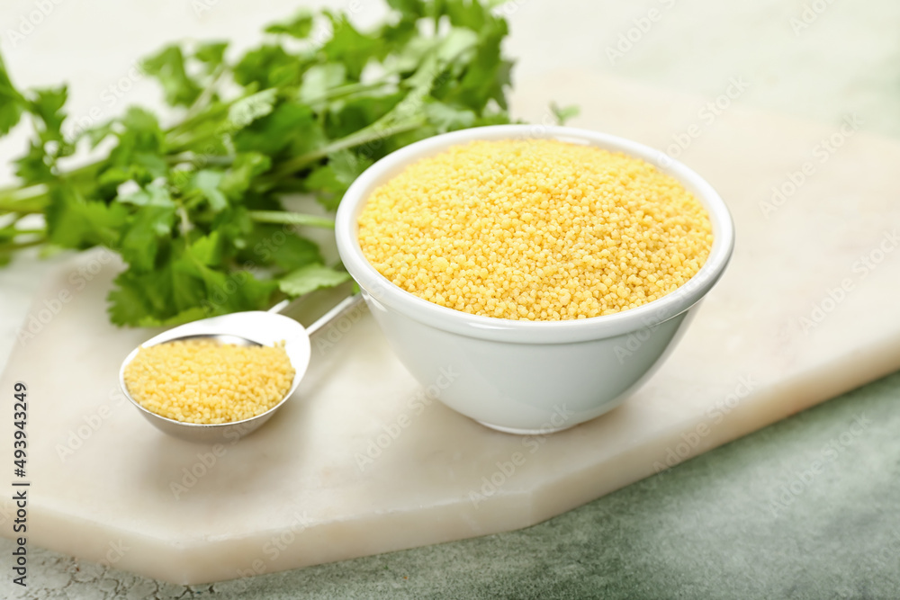 Bowl and spoon with raw couscous with parsley on grunge background Bowl and spoon with raw couscous with parsley on grunge background