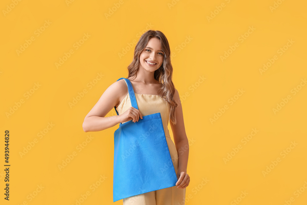 Young woman with blue eco bag on yellow background Young woman with blue eco bag on yellow background