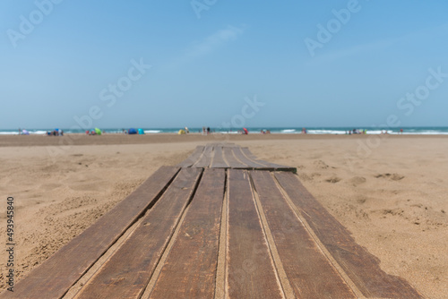 Selective focus of a wooden path on the beach with the sea in the background