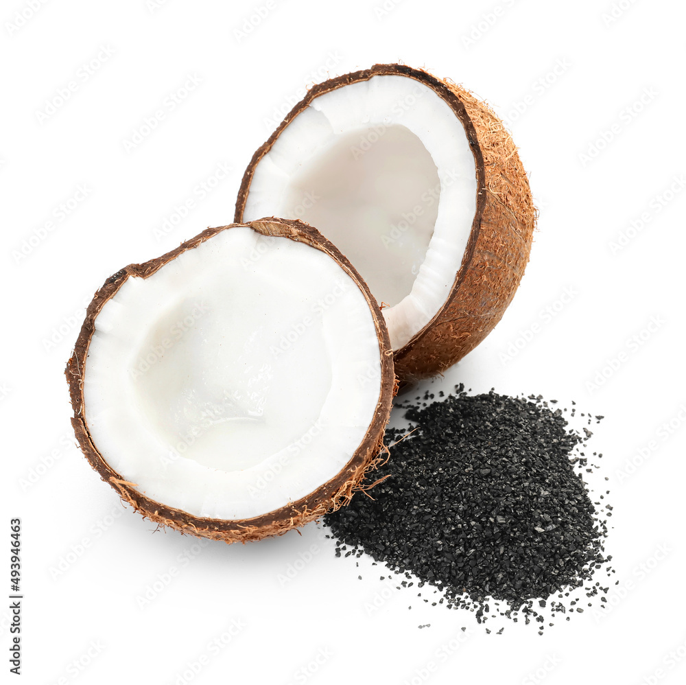 Ripe coconut halves with pile of activated carbon on white background Ripe coconut halves with pile of activated carbon on white background
