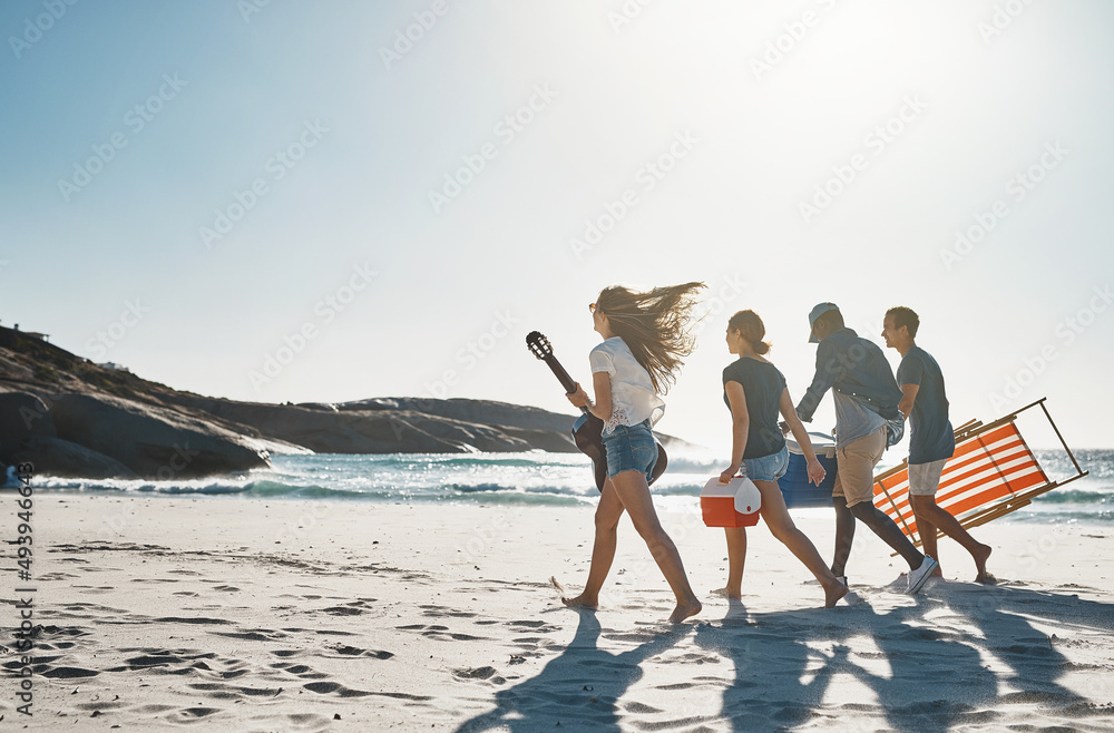 Fototapeta premium Happiness is a day spent at the beach. Shot of a group of young friends walking on the beach on a sunny day.
