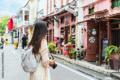 Happy Asian traveler woman take a photo while walking on the city street. Travelling in Phuket Old Town in Thailand concept photo