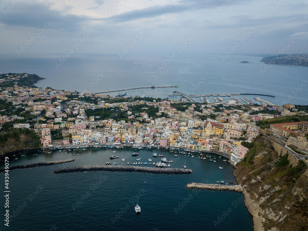Colored boats anchored at small seaside town quay (aerial drone photo). Mediterranean, Procida, Italy
