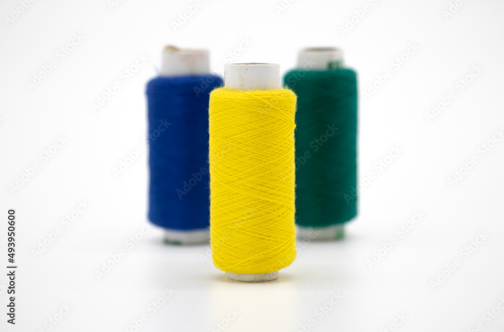 Sewing thread and bobbin in yellow color on isolated white background Sewing thread and bobbin in yellow color on isolated white background